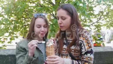 两个年轻的女人坐在公园里吃冰淇淋